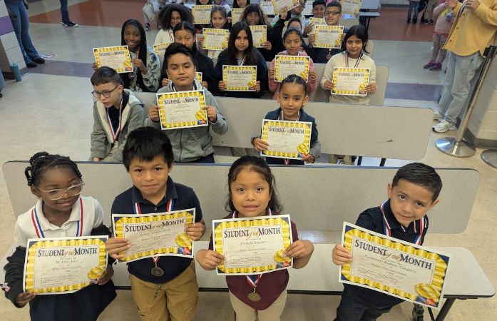 Students sitting with student of the month certificates and smiling.